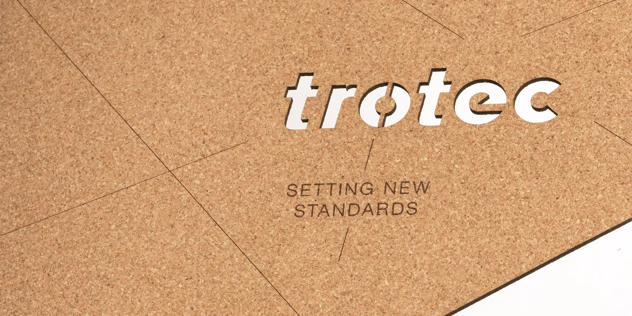 Plancha de corcho Trotec cortada con láser con el eslogan grabado "Setting New Standards" (Estableciendo nuevos estándares)